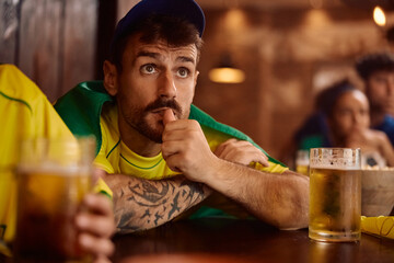 Focused sports fan watching  match on TV in bar.