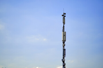 Obraz premium Telecommunication tower with antennas against a clear blue sky. Outdoor technology photography.