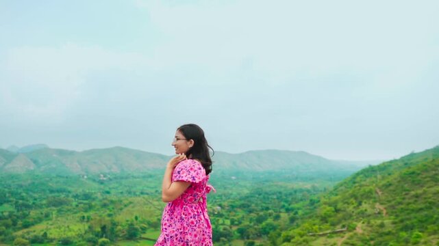 Beautiful Indian young woman walking and green hills in background at Rayta Hills, Udaipur, India. Tourist enjoying holiday. 