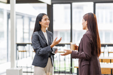 Fototapeta premium Two young asian women holding digital tablet and working in modern office 
