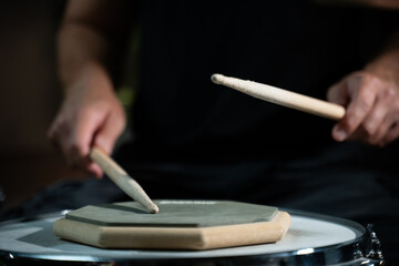 A person is practicing using drumsticks on a training pad. They are using a single drumstick and...