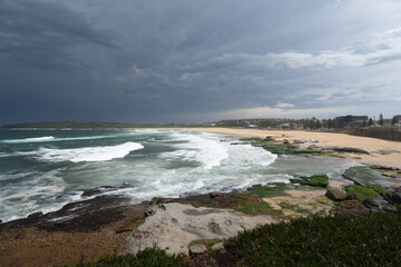 Storm over the ocean beach with green mossy rocks