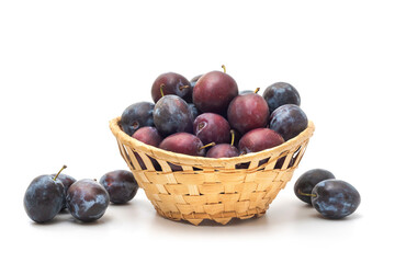 Fresh plums in basket on white background. Ripe organic fruits
