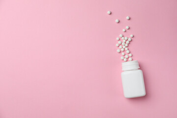 Homeopathic remedy. Overturned plastic bottle and pills on pink background, top view. Space for text
