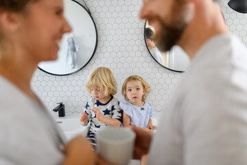 Fototapeta premium Parents and kids having morning bathroom routine, brushing teeth and washing face, enjoying together time.