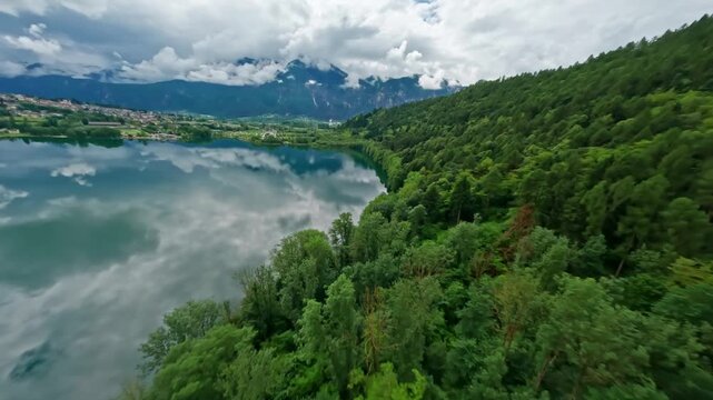 Lago di levico with lush green forest and mountains in the background, aerial view