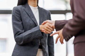 Obraz premium Two happy professional business women executive leaders shaking hands at office meeting. Smiling business woman standing greeting partner with handshake. Leadership, trust, partnership concept.