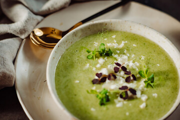 Delicios green soup decorated with micro vegetable on a wooden table. 