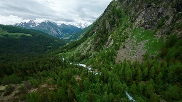 Cascate del rutor waterfalls in lush green valley surrounded by mountains, aerial view