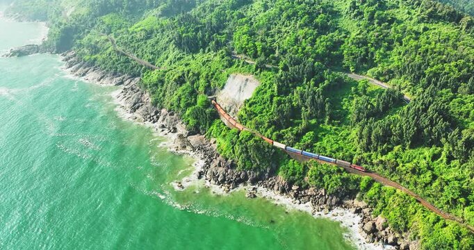 Aerial view of train and railway on Hai Van pass, Bach Ma mountain, Hue, Vietnam. Spectacular view of train crossing the dense tropical forest covering the remote Asian island. Beautiful shoreline.