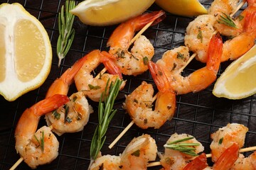 Skewers with delicious grilled shrimps, herbs and lemon on wooden table, flat lay