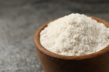 Organic coconut flour in bowl on grey table, closeup. Space for text