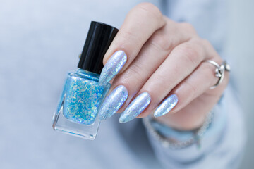 Female hand with long nails and bright light blue and silver manicure	