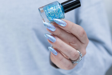 Female hand with long nails and bright light blue and silver manicure	