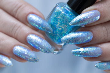 Female hand with long nails and bright light blue and silver manicure	