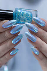 Female hand with long nails and bright light blue and silver manicure	