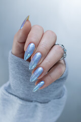 Female hand with long nails and bright light blue and silver manicure	