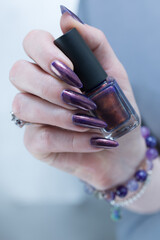 Beautiful woman's hand with long nails and multicolored nail polish, purple and brown 