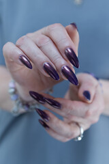 Beautiful woman's hand with long nails and multicolored nail polish, purple and brown 