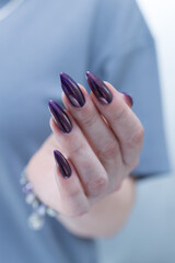 Beautiful woman's hand with long nails and multicolored nail polish, purple and brown 