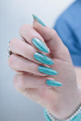 Female hand with long nails and light turquoise manicure, blue and green color