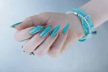 Female hand with long nails and light turquoise manicure, blue and green color