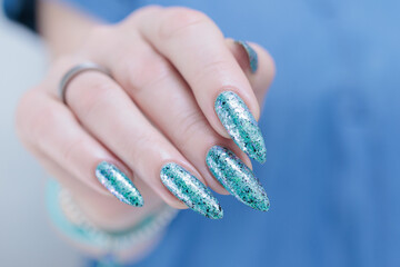 Female hand with long nails and light green and blue turquoise manicure 