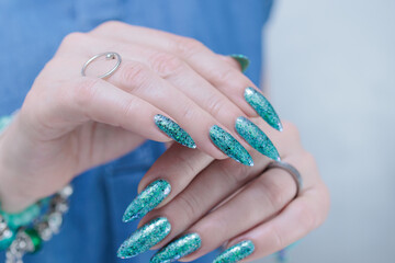 Fototapeta premium Female hand with long nails and light green and blue turquoise manicure 