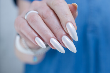 Woman's hands with long nails and a light white color nail polish