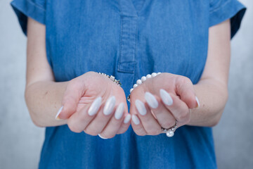 Woman's hands with long nails and a light white color nail polish