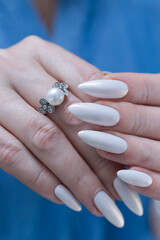 Woman's hands with long nails and a light white color nail polish