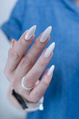 Woman's hands with long nails and a light white color nail polish