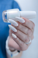 Woman's hands with long nails and a light white color nail polish