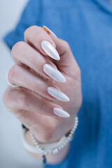 Woman's hands with long nails and a light white color nail polish