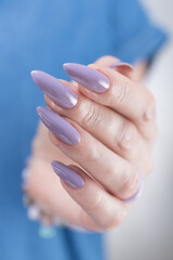Fototapeta premium Female hand with long nails and a lilac nude nail polish