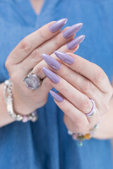 Female hand with long nails and a lilac nude nail polish