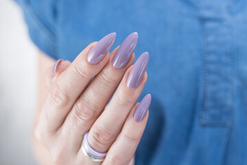 Female hand with long nails and a lilac nude nail polish