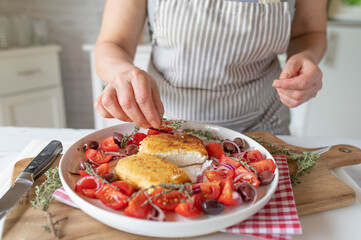 Fresh and homemade breaded feta cheese with tomato olive salad prepared by woman´s hands in the...