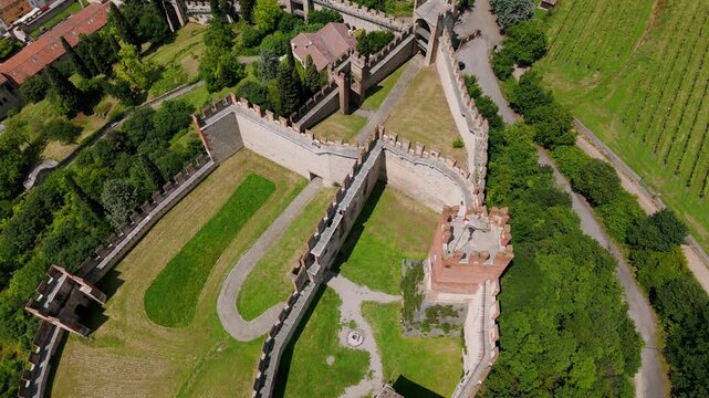 Aerial overhead view showcasing the historic Soave Castle in Italy, surrounded by lush greenery and ancient walls on a bright sunny day.