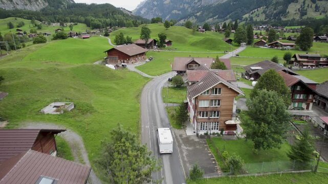 Camper driving through a picturesque Swiss village with lush green landscapes