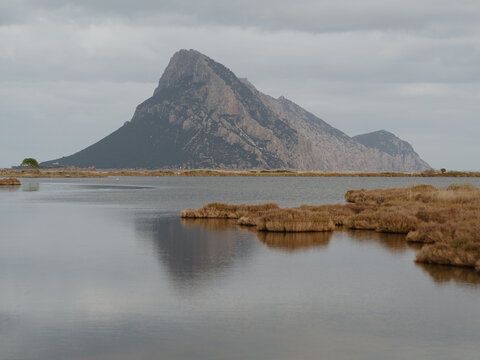 Mediterranean off-season: Tavolara Island reflected in still waters of Porto Taverna beach near San Teodoro, Sardinia, Italy.