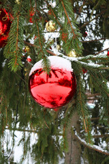 Christmas tree on a city street with red balls covered with snow