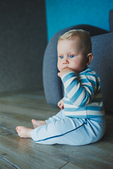 Fototapeta premium Happy smiling child. A cute little newborn baby boy with a smiling face is crawling on the floor. Motherhood baby care concept happy baby