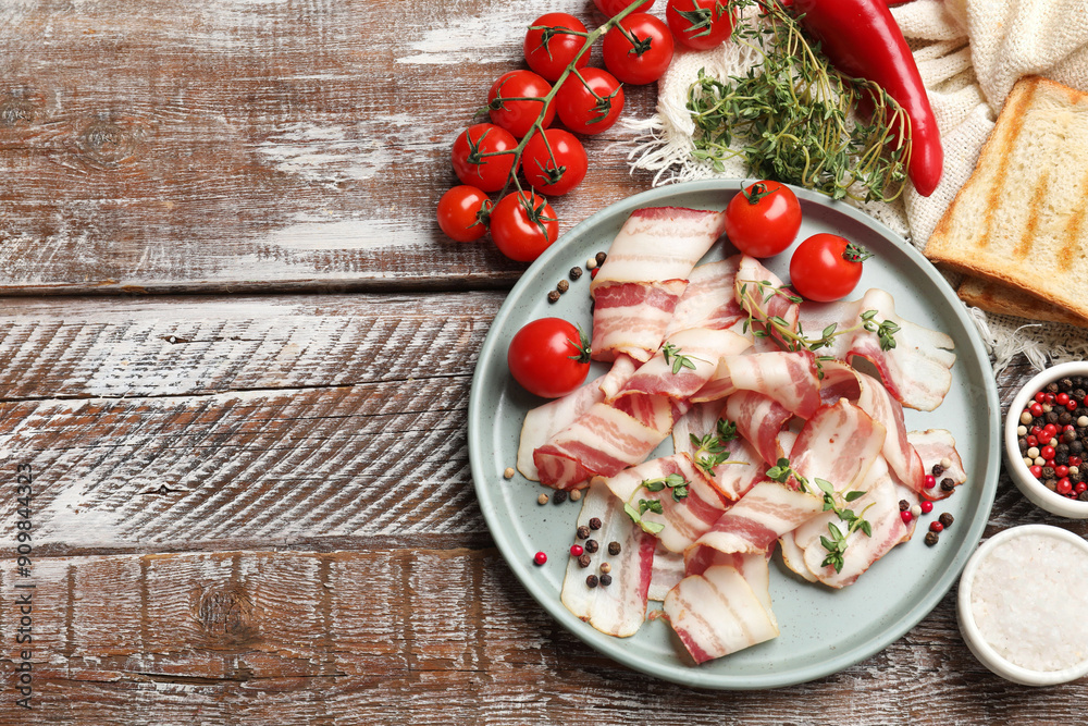 Sticker slices of raw bacon, spices, bread and tomatoes on wooden table, flat lay. space for text