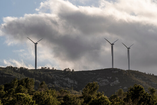 An image capturing three wind turbines atop a hill, producing renewable energy under a dramatic cloudy sky, illustrating nature and sustainable technology in Tarragona Spain