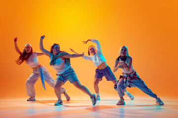 Group of energetic dancers in casual retro outfits performing contemporary dance in vibrant neon light against gradient studio background. Concept of music, fashion and art, movement, sport and hobby.