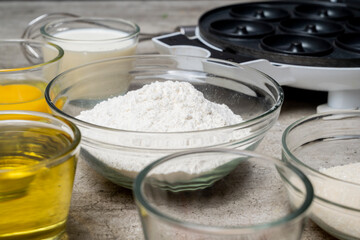 A table with several bowls of ingredients, including flour, sugar, and oil