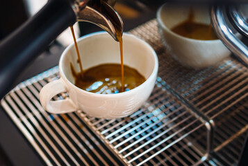 Close-up of espresso pouring from the coffee machine into a coffee cup. Professional coffee brewing