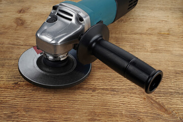 Electric angle grinder on a wooden background.