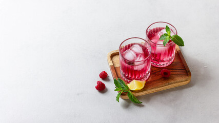 Raspberry cocktail with ice in a glass on a light background
